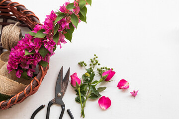 pink rose flower , purple bougainvillea glabra, scissors and basket arrangement flat lay postcard...