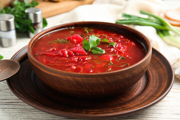 Stylish brown clay bowl with Ukrainian borsch served on white wooden table