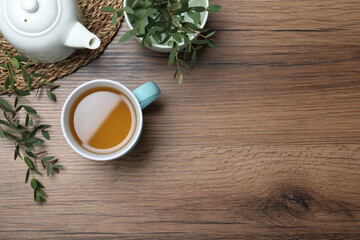 Aromatic eucalyptus tea on wooden table, flat lay. Space for text
