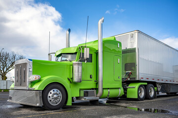 Bright green classic American Idol big rig semi truck tractor with shiny chrome parts and high...