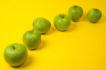 Large green apples, ripe and juicy. Photographed against a uniform yellow background.