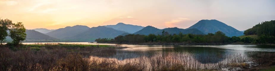 panorama beautiful landscape hills and meadow with orange sky reflection in water. mountain lake in the sunset. © TongTa