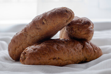 three freshly baked rye bread rolls on a white cloth napkin