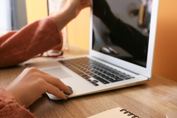 Woman working with laptop on table at home