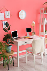 Stylish workplace with laptop near color wall in office