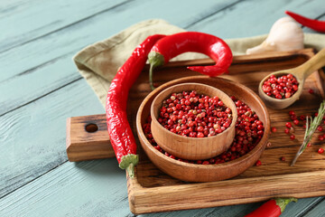 Bowls with red peppercorns on color wooden background