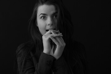 Black and white portrait of a young brunette woman in a studio on a black background