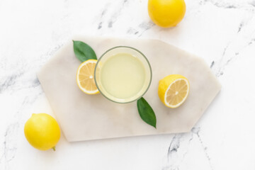 Fresh lemons and glass of juice on light background