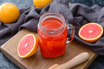Mason jar of grapefruit juice on color background