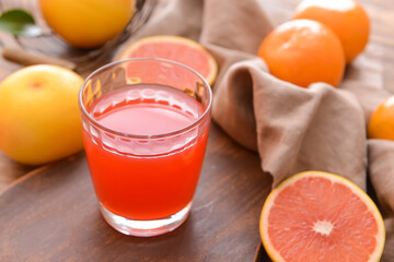 Fresh grapefruits and glass of juice on wooden background