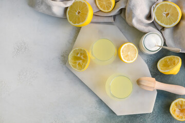 Obraz na płótnie Canvas Fresh lemons and glasses of juice on light background
