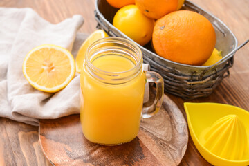 Mason jar of orange juice on wooden background