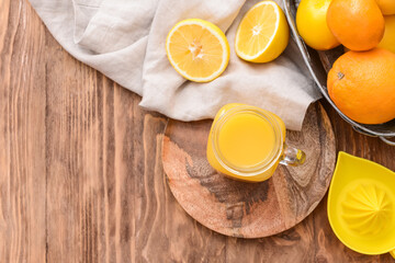 Mason jar of orange juice on wooden background