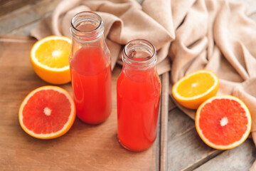 Bottles of grapefruit juice on wooden background