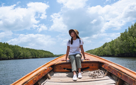 Portrait image of a beautiful young asian woman sitting on a long tail boat while traveling the sea and mangrove forest