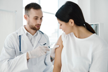 Fototapeta premium doctor with a stethoscope injections in the patient's shoulder coronavirus epidemic infection