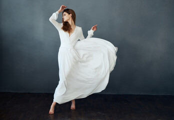 Woman on a gray background in a white dress dance model in full growth