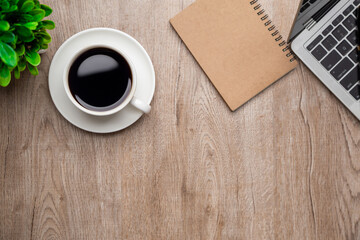 Flat lay, top view office table desk. Workspace with, laptop,office supplies, pencil, green leaf, and coffee cup on wood background.