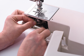 the seamstress inserts the bobbin into the sewing machine. close-up.