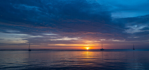 Fototapeta na wymiar Boats on the sea at sunset. Sailboats with sails. Ocean yacht sailing along water.