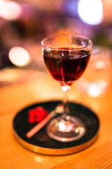 A red alcoholic cocktail in a nick and nora glass served on a tray with cranberry garnish. A lifestyle photo with shallow depth of field.