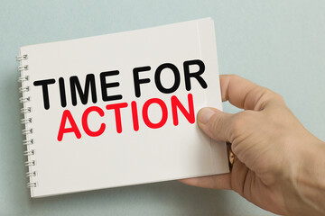 THE WORLDS TIME FOR ACTION written on the notebook. Notebook in hand on a blue background.