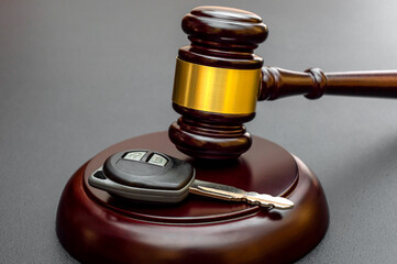 Judge's gavel with car key on black. Car auction and insurance concept.