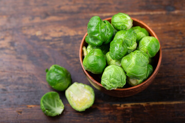 Bunch of fresh Bruxelles sprouts in a cup on wooden background.