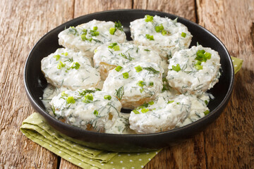 Boiled potatoes with cottage cheese and yogurt sauce and herbs close-up in a bowl on the table. horizontal