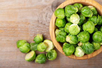 Fresh raw brussels sprouts in a bowl on a wooden table.