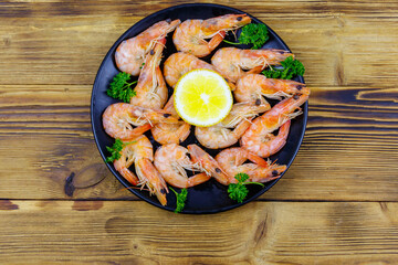 Red boiled prawns with lemon and parsley on wooden table. Top view