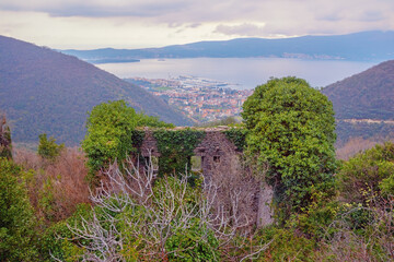 Cloudy day. Old ruined house in mountains against beautiful Mediterranean landscape. View of Tivat city, Montenegro