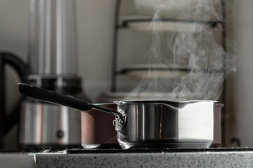 Stainless steel pot on an electric stove in the kitchen. Selective focus, blurred background.