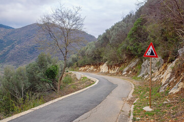 Balkan road trip. Old country road with a sign of falling stones. Montenegro