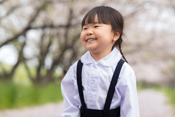 満開に咲いた桜の並木と幼稚園の制服を着た女の子