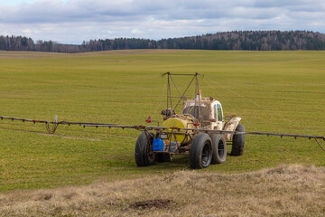 Obraz premium Street lighting. special machine on wheels for gentle spraying of crops in the field. Filled with fertilizer for plants.