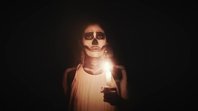 Catrina Girl Candles day of the dead in mexico 2 4k.mov	light, spiritual, makeup, dark, woman, candles, candle, fire, candlelight, flame, face, people, black makeup, chandelier, body painting, body pa