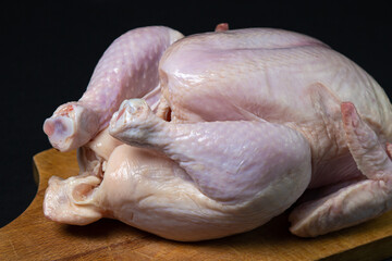 Chicken carcass on a black background. Chicken meat on a wooden board. Diet meat.