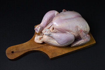 Chicken carcass on a black background. Chicken meat on a wooden board. Diet meat.