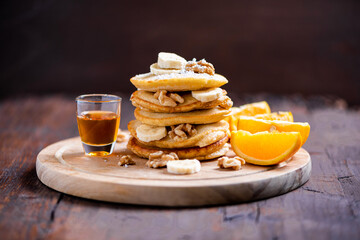 Stack of pancakes with honey, nuts and oranges
