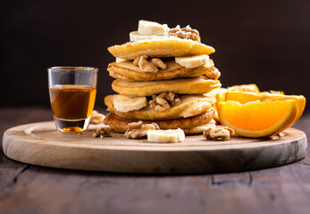 Stack of pancakes with honey, nuts and oranges
