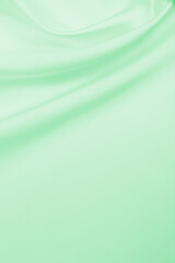 Smooth elegant green silk or satin luxury cloth texture as abstract background. Luxurious background design