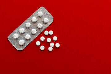 Medical pills on red background.