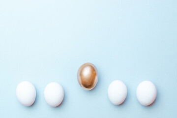 Easter gold. Golden, white colour egg on pastel blue background in Happy Easter decoration. Traditional design in top view.