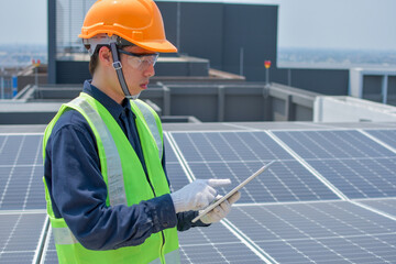 An engineer who works on the inspection and maintenance of equipment at roof-mounted solar power plants of condominium buildings, houses with a tablet in his hand.