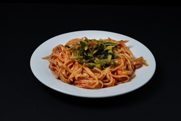 Spaghetti in tomato sauce on a dark background. Spaghetti with a vegetable side dish on a black background. Italian food. Tasty food