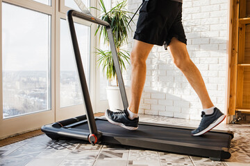 Man jogging on the modern compact treadmill at his home