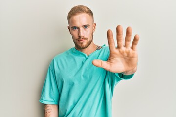 Young caucasian man wearing casual clothes doing stop sing with palm of the hand. warning expression with negative and serious gesture on the face.