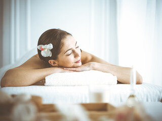 Fototapeta na wymiar Beautiful brunette woman enjoying back massage with closed eyes comfortable and blissful. Spa and medicine concept