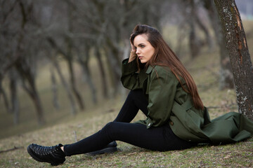 Image of young beautiful woman wearing rain jacket in cold weather. Thinker european girl in spring nature.